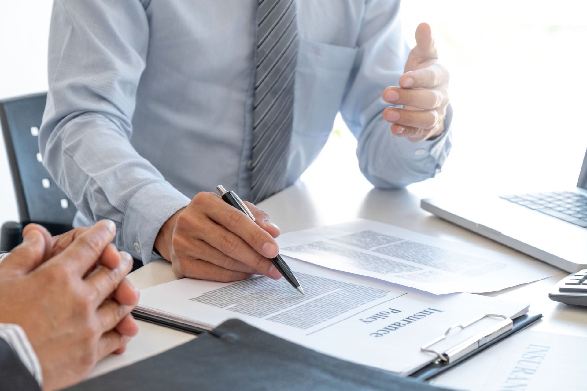 Two people in business attire reviewing documents and discussing work at an office desk.