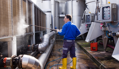 Un hombre está limpiando un edificio con una hidrolavadora.