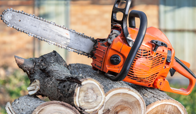 Una motosierra está colocada encima de una pila de troncos.