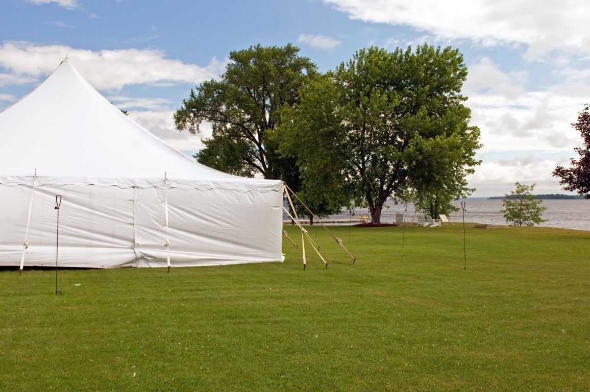 A white tent is sitting in the middle of a grassy field.