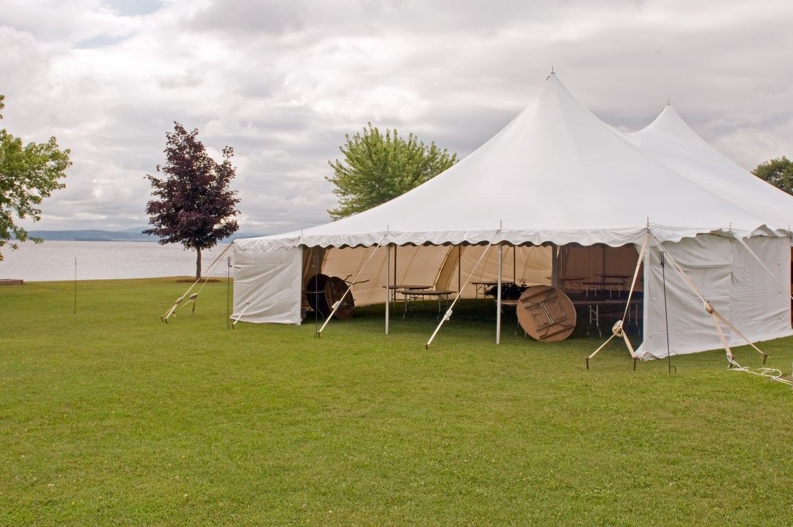 A large white tent is in the middle of a grassy field