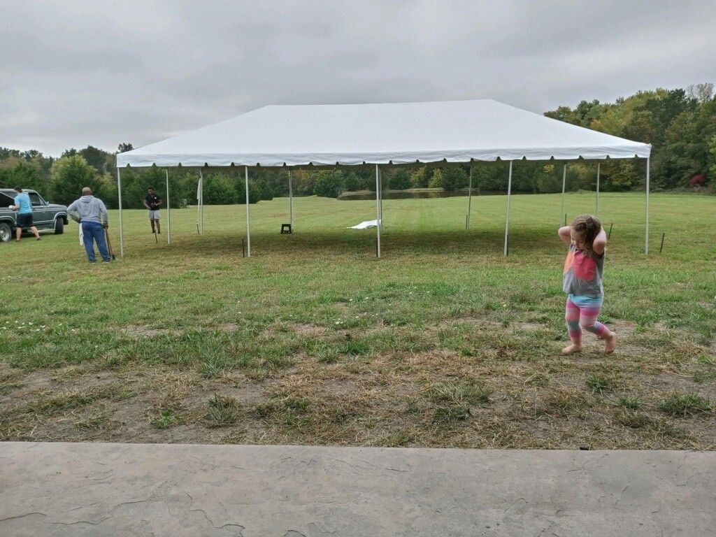 A little girl is throwing a frisbee in a field under a tent