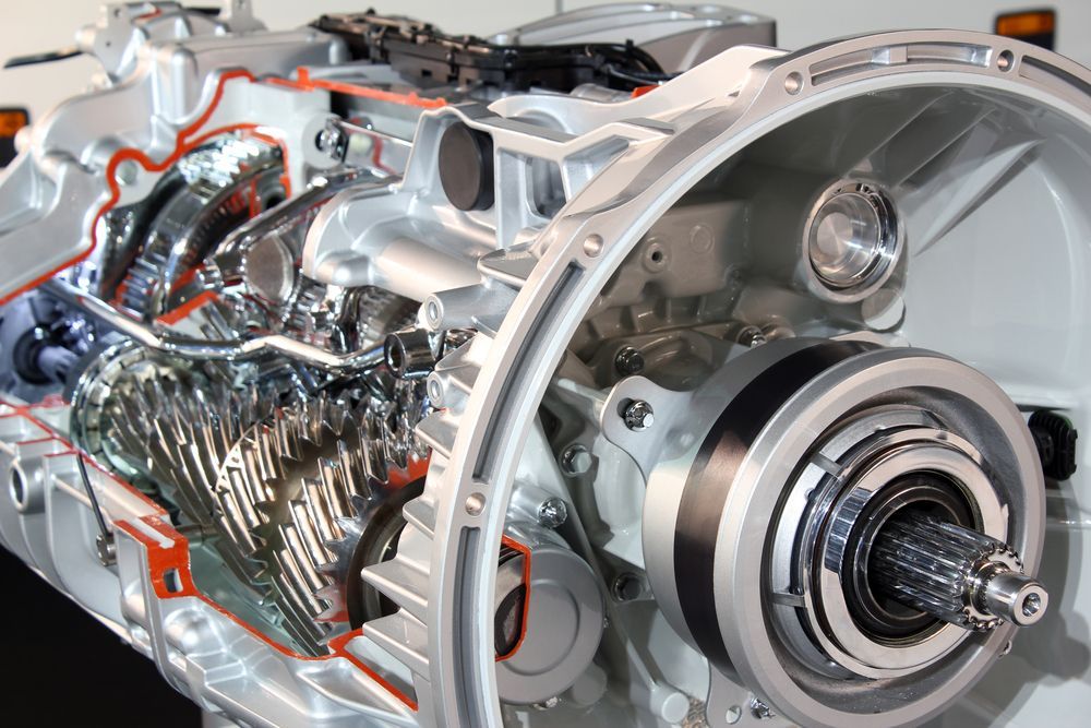 Cutaway view of an automotive transmission, showcasing gears, shafts, and internal components; mostly silver.