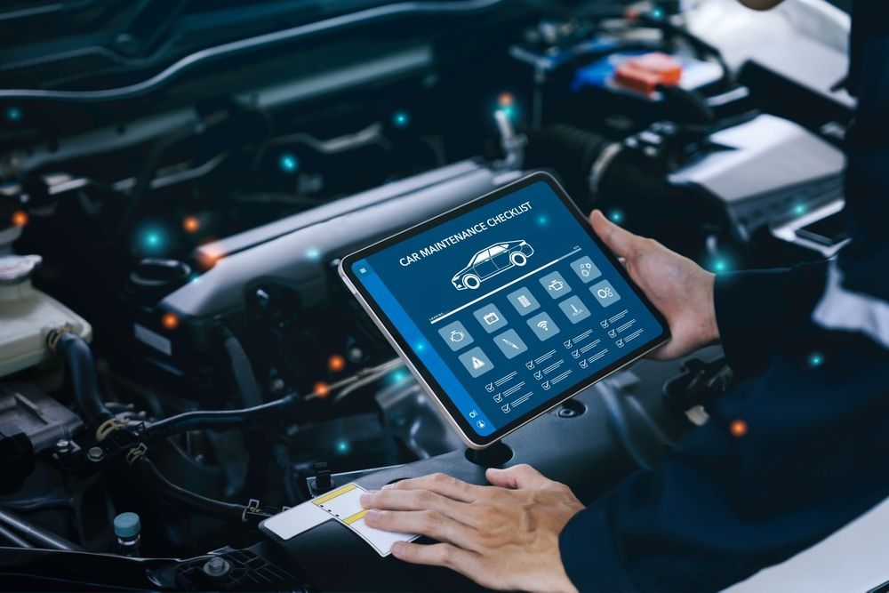 Mechanic using a tablet to diagnose a car engine. The tablet displays diagnostic information.
