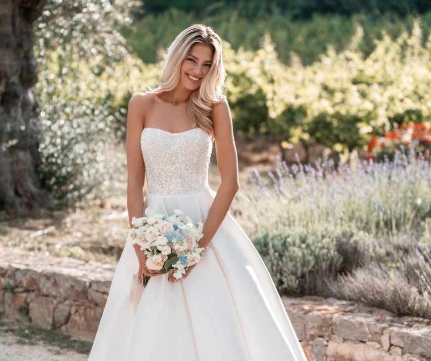 A woman in a wedding dress is standing in a field of flowers.