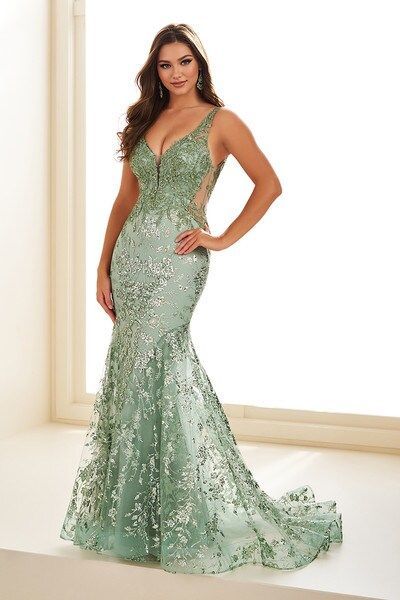 A woman in a green dress is standing in front of a window.