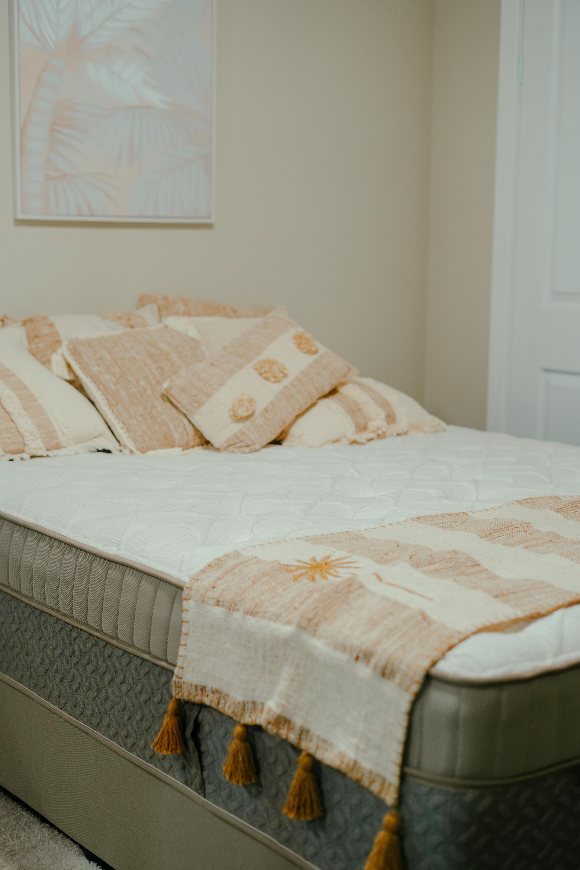 Bed with cream and gold pillows and runner, painting on wall — Coastal Mattress' Direct in Brisbane, QLD  