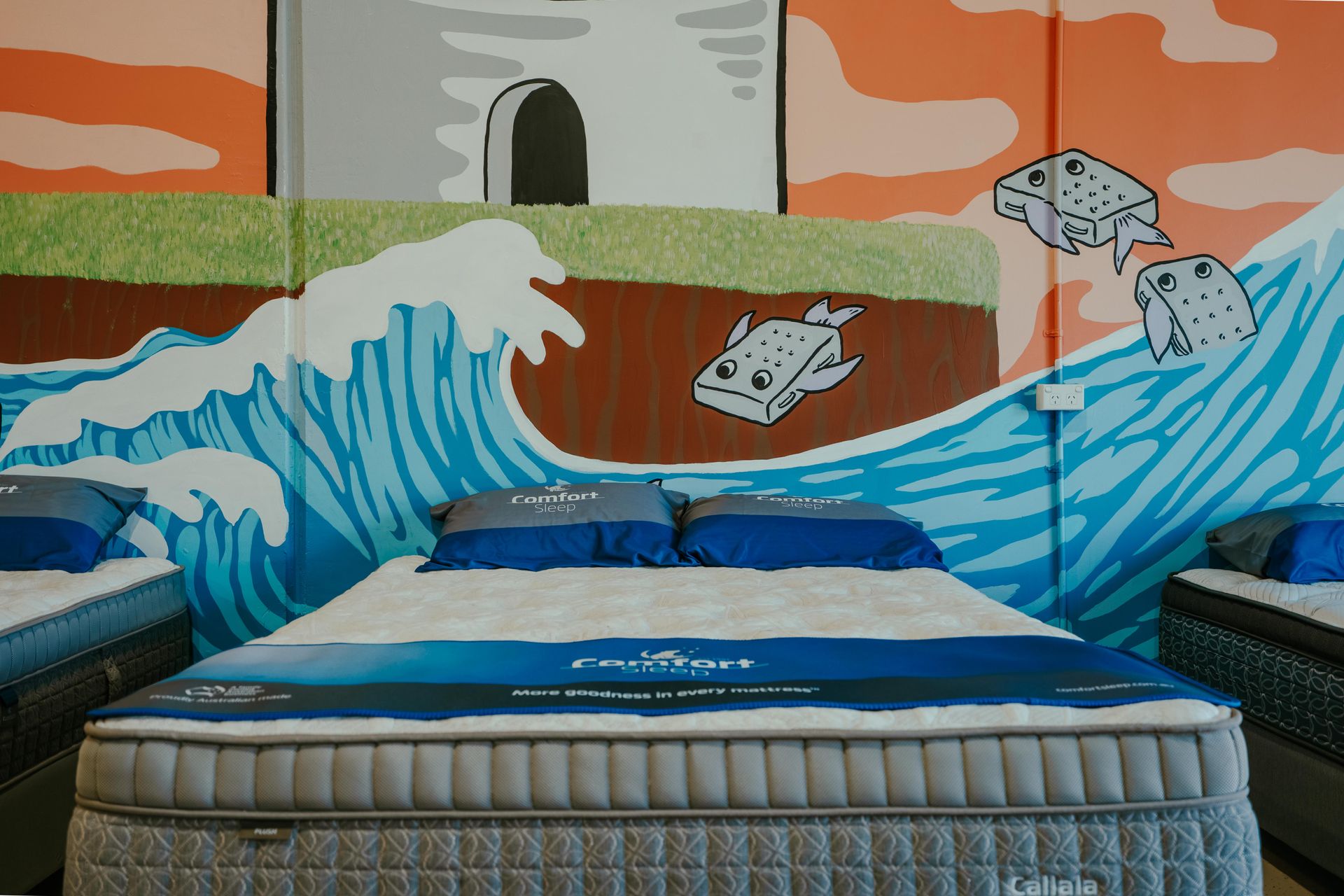 Mattress showroom with several beds displayed, colorful mural on the wall, and high ceilings — Coastal Mattress' Direct in Brisbane, QLD  