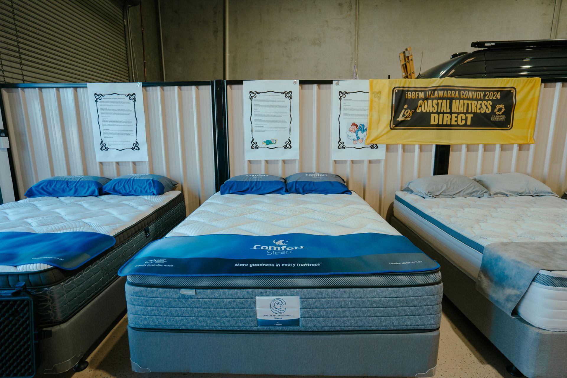 Mattresses on display at a store, with blue and white bedding, and signs on the wall — Coastal Mattress' Direct in Brisbane, QLD