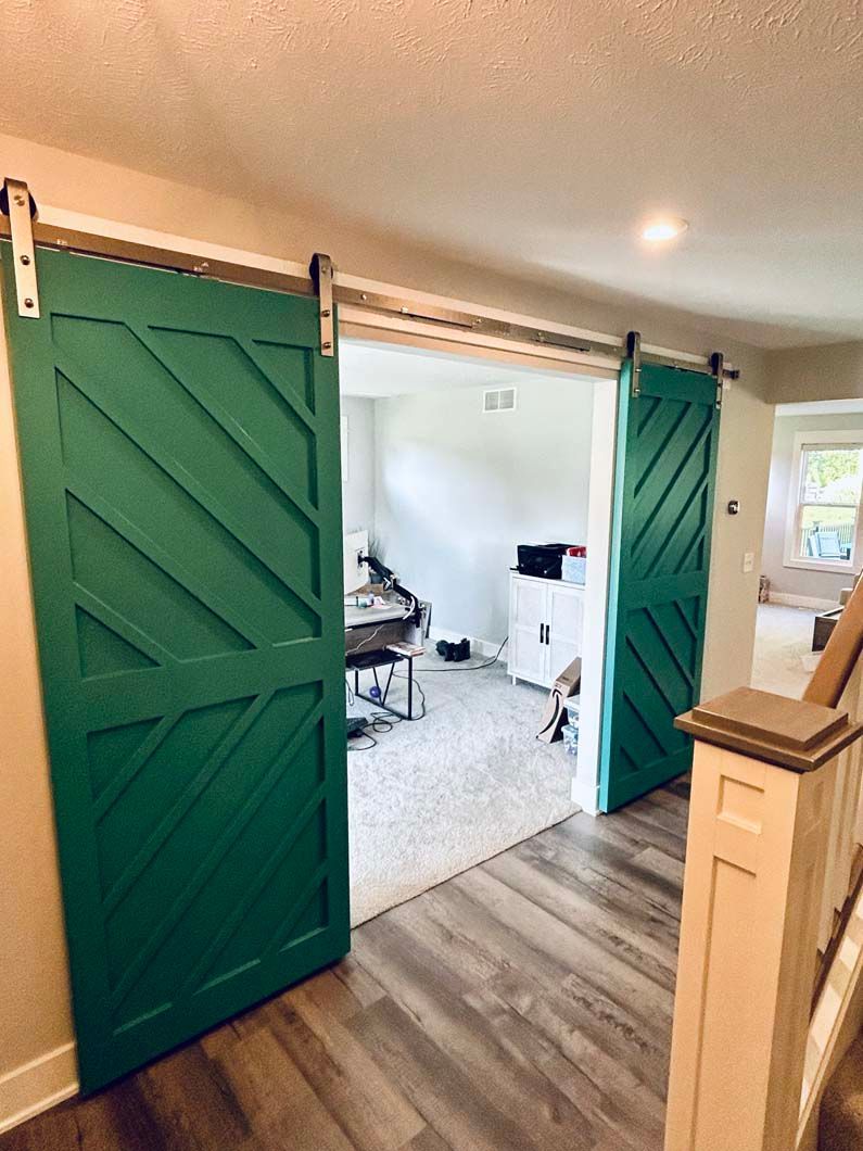 A hallway with green sliding barn doors leading to a living room.