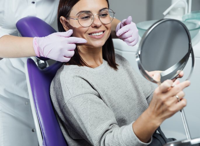 woman smiling in dentist chair looking in mirror after getting dental crowns | Coraopolis PA