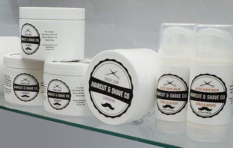 A variety of shaving products are sitting on a glass shelf.