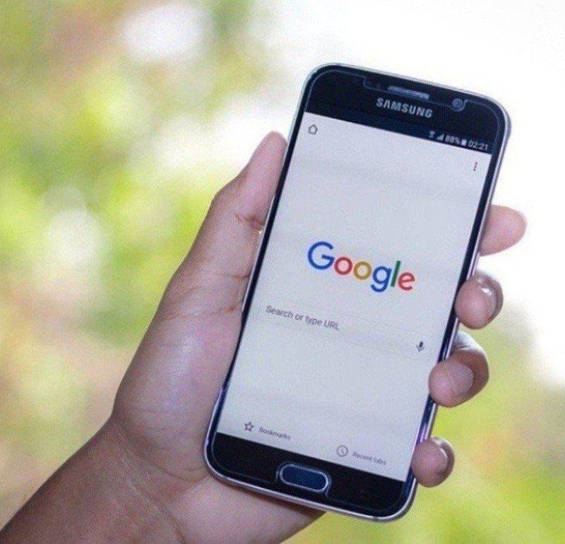 A person is holding a samsung phone with google on the screen