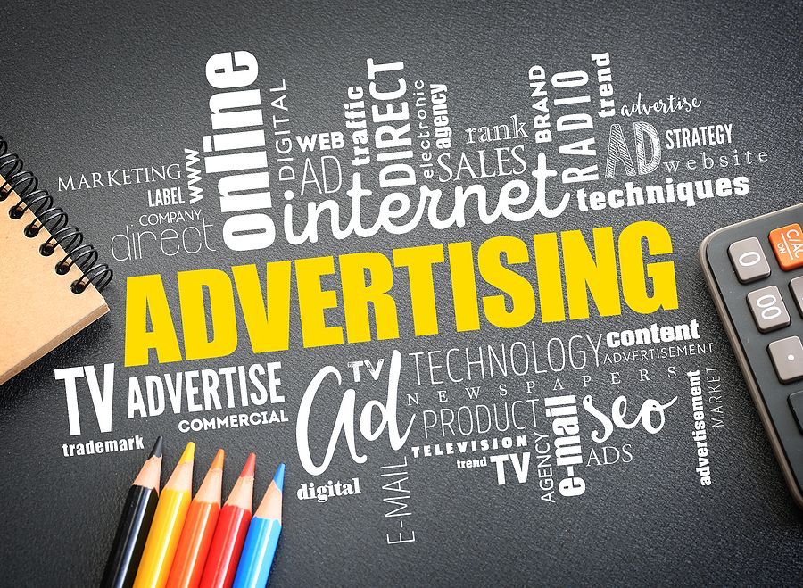 The word advertising is written on a blackboard with pencils and a remote control.