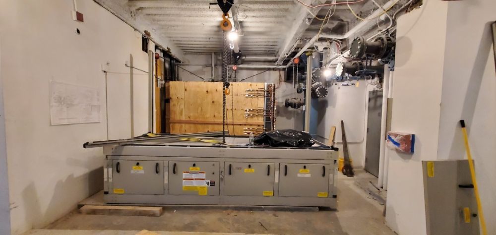 Large industrial machine in a room under construction with wooden crates in the background.