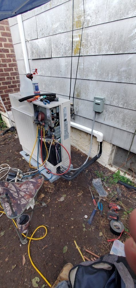 An HVAC unit being serviced outside a building with exposed components and tools scattered around.