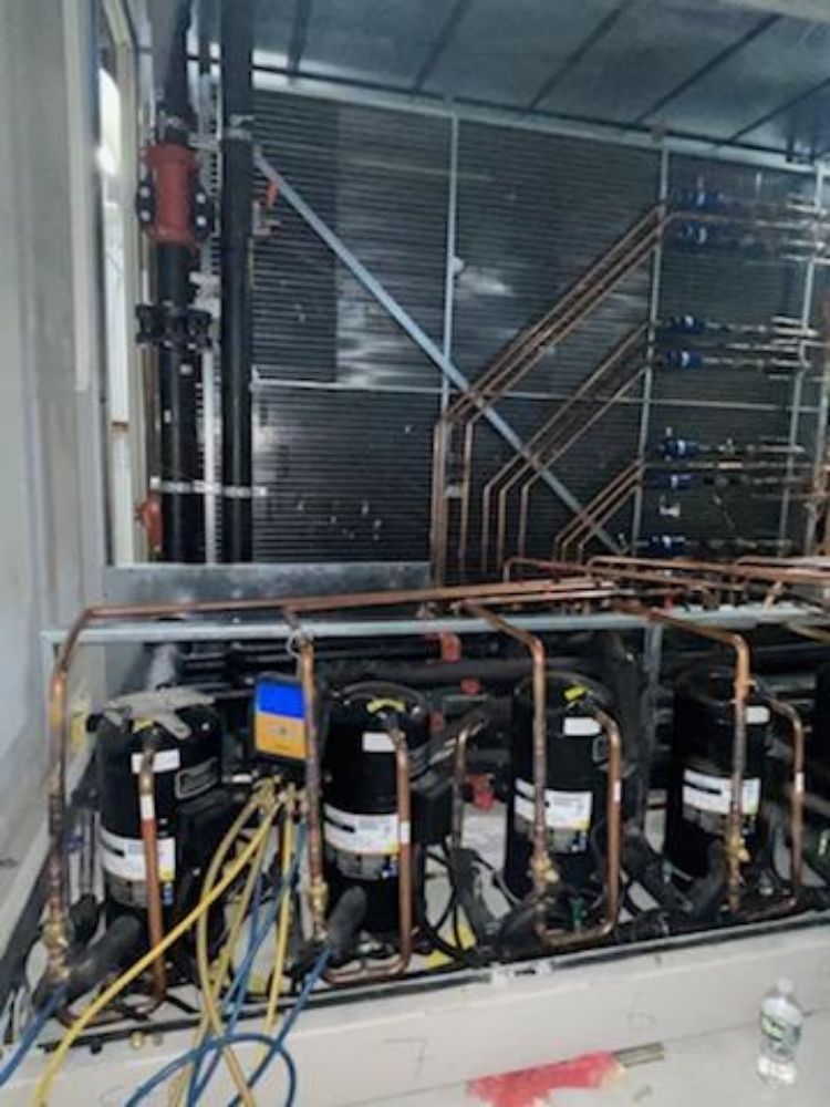 Industrial refrigeration unit with copper piping, electrical wiring, and a large condenser coil.
