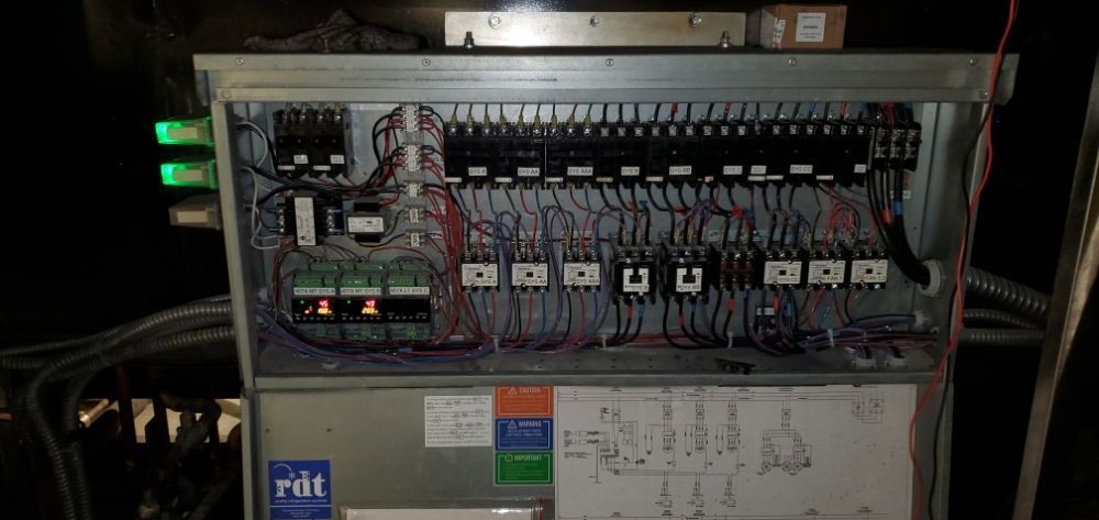 An electrical panel with numerous wires, switches, and components inside a metal enclosure.
