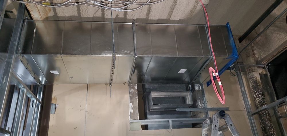 HVAC system installation in a construction site: ductwork, framework, and a ladder are visible.