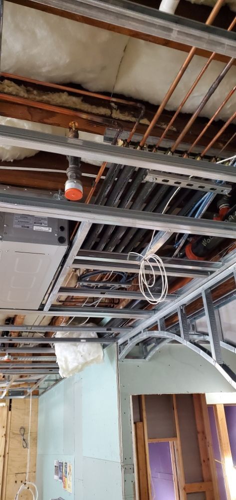 Interior ceiling under construction, metal framing, exposed pipes, and insulation.