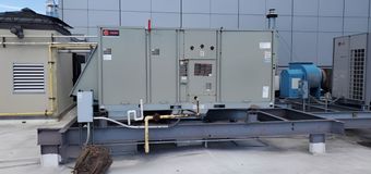 White wall-mounted air conditioner unit installed near a white ceiling.