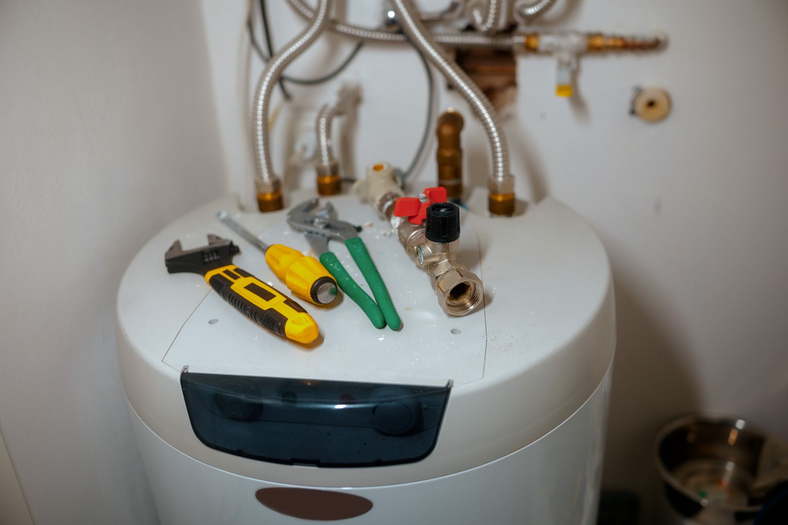 Tools and plumbing components on top of a water heater.