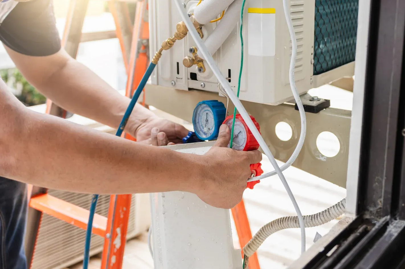 Person using gauges to service an air conditioner unit, outside.