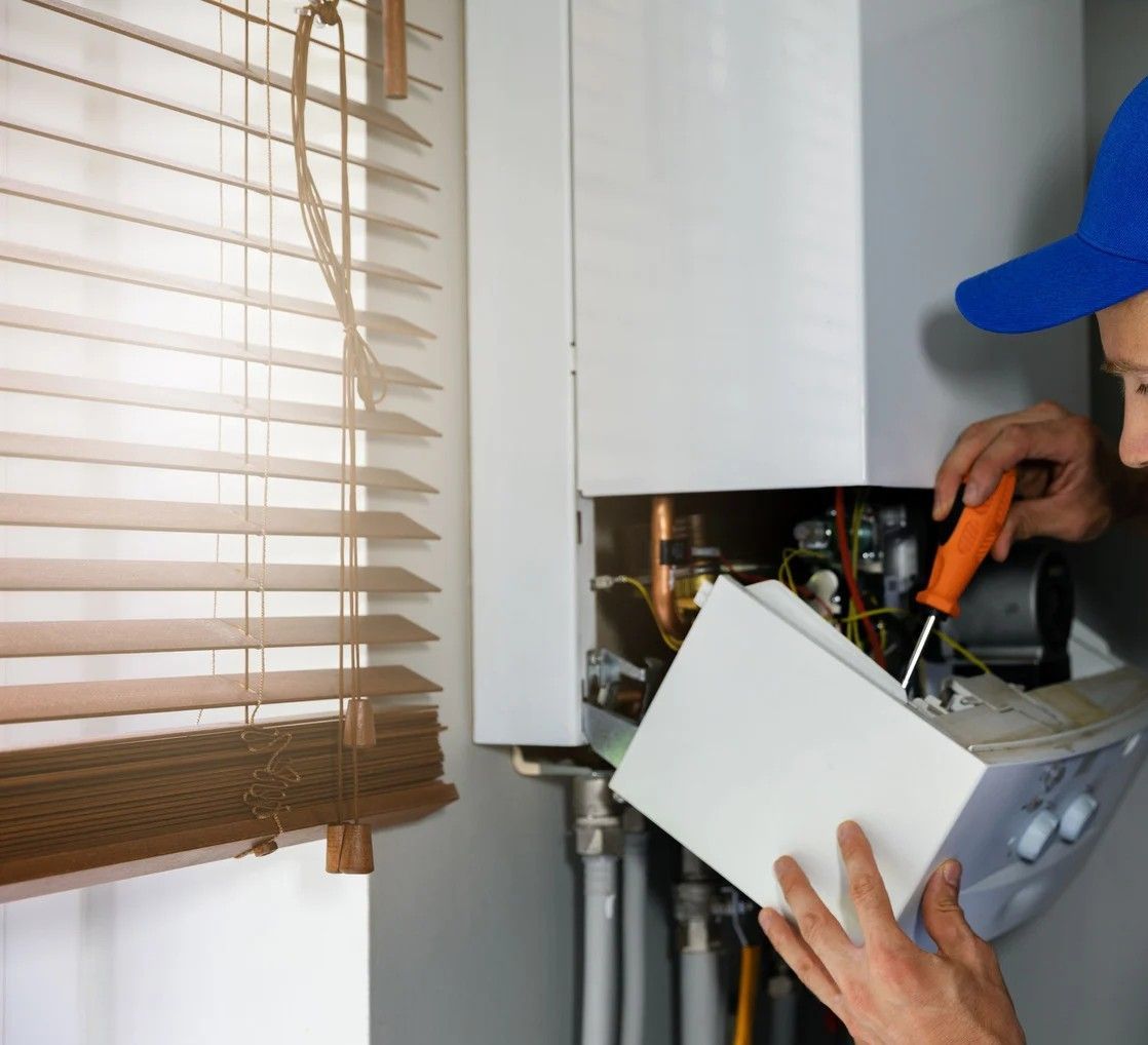 Person working on the pipes of a water heater with tools; interior shot.
