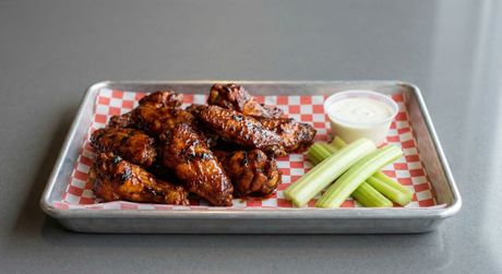A wooden cutting board topped with chicken wings and celery sticks