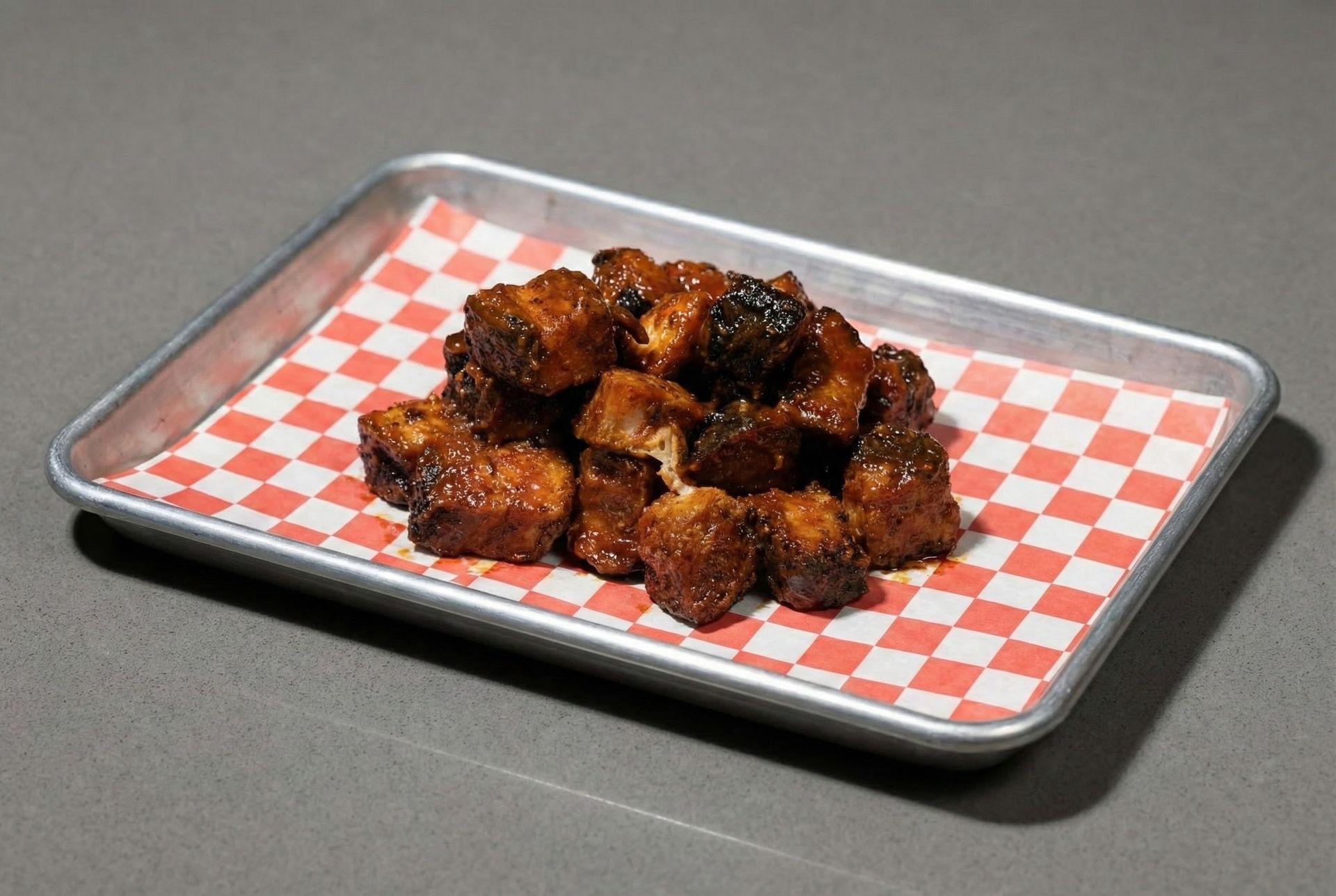 A pile of meat cubes on a wooden cutting board.