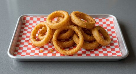 A wooden cutting board topped with chicken wings and celery sticks