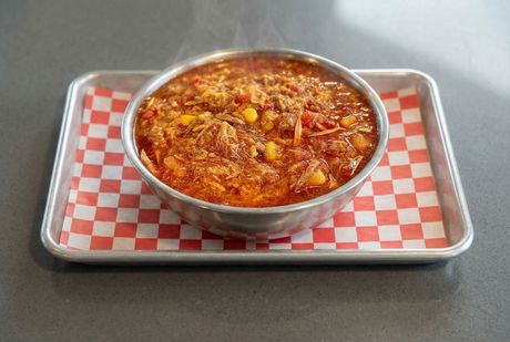 A bowl of curry is sitting on a black table.