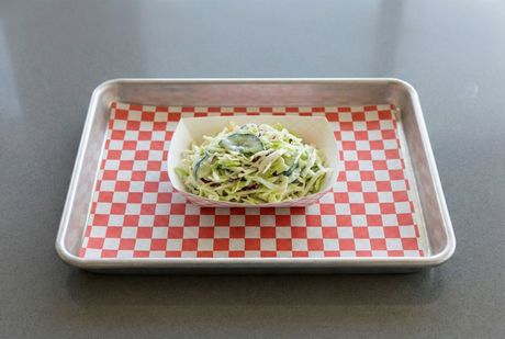 A bowl of cabbage and a bowl of mustard on a table.