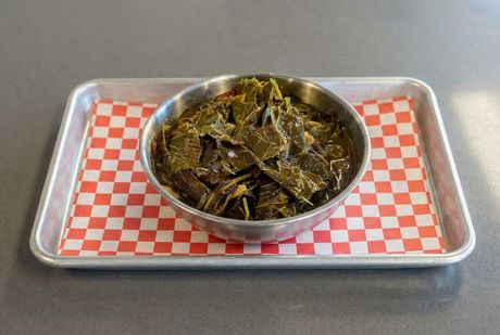 A bowl of food next to a bunch of green leaves on a table.