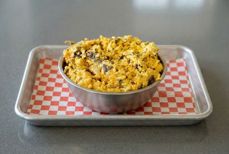 A bowl of food is sitting on a table next to spices.