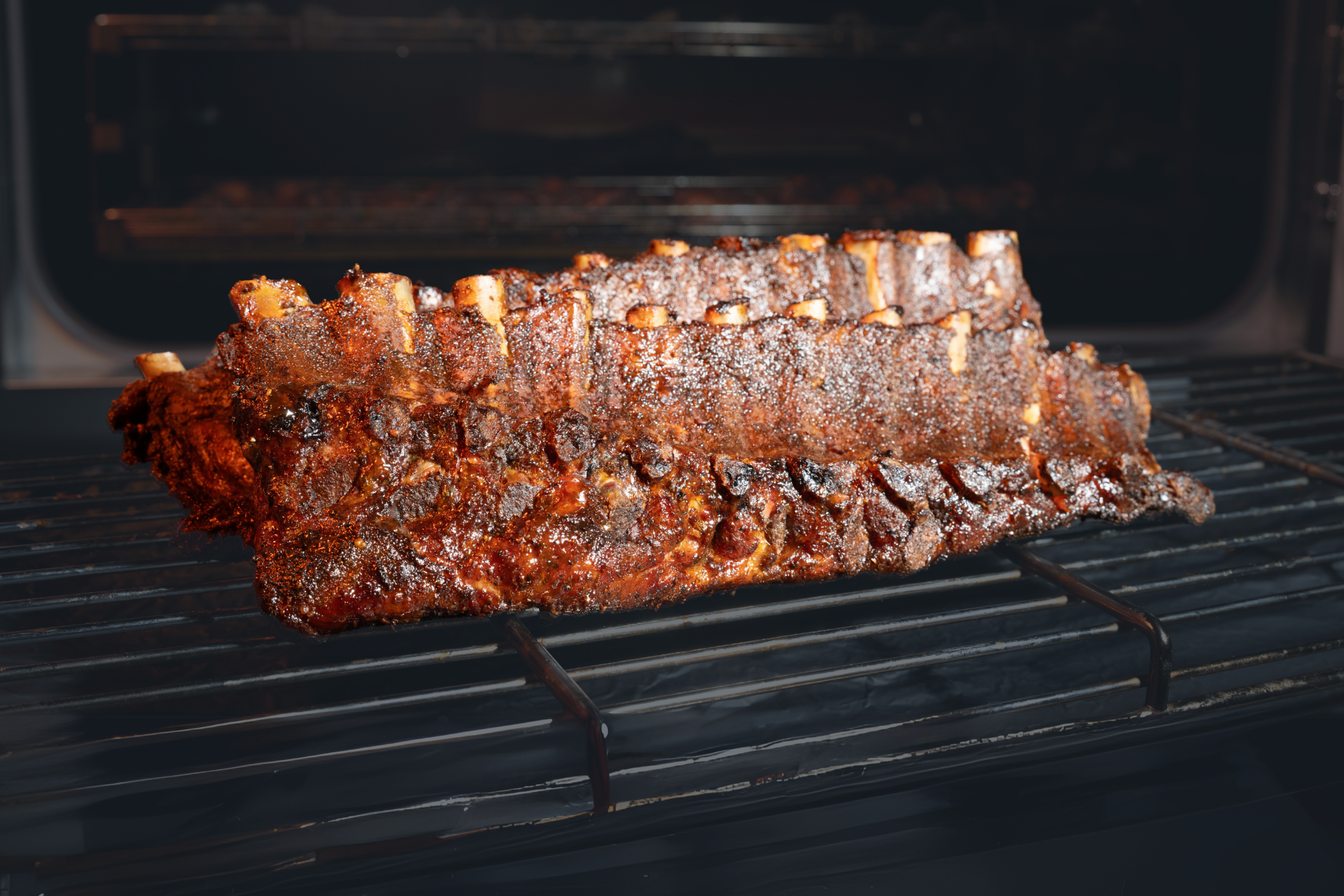 A rack of ribs is cooking on a grill in an oven.