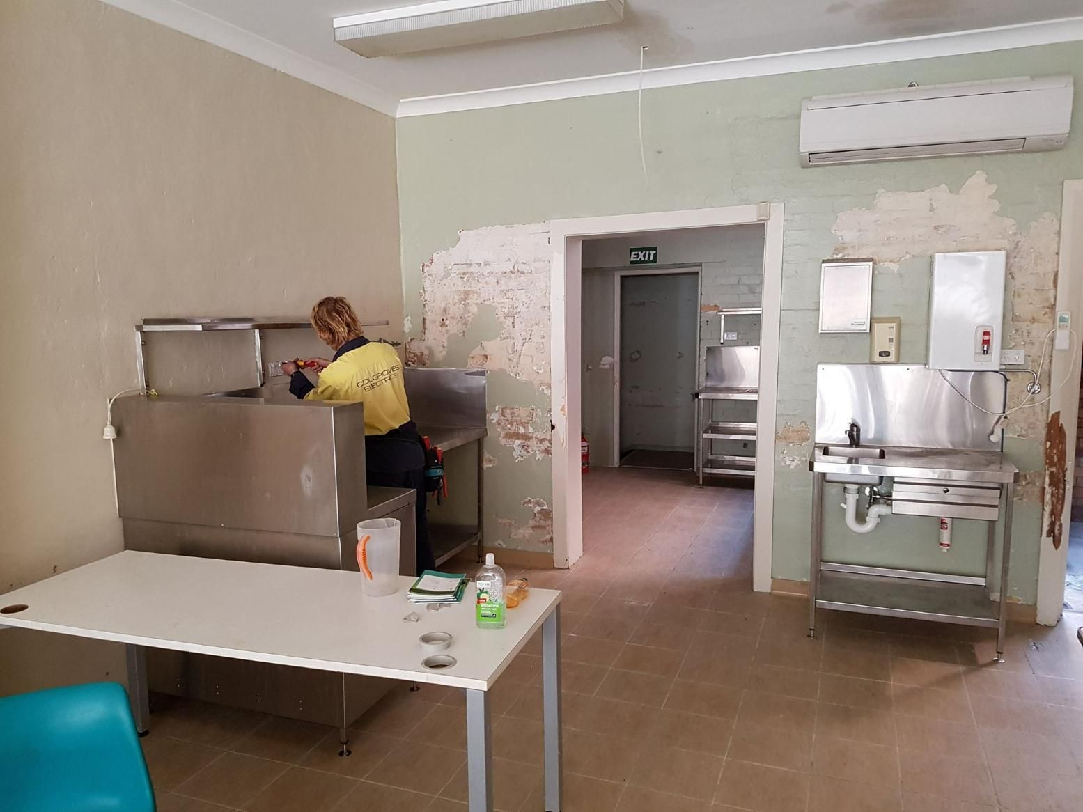 A Woman Is Working on A Stainless Steel Dishwasher in A Kitchen — Col Groves Electrics Pty Ltd in Ballina, NSW