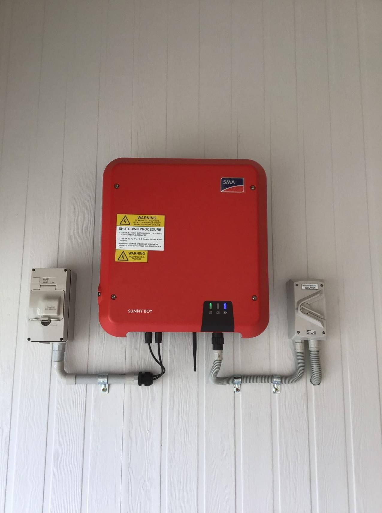 A Red Solar Inverter Is Mounted on A White Wall — Col Groves Electrics Pty Ltd in Wollongbar, NSW