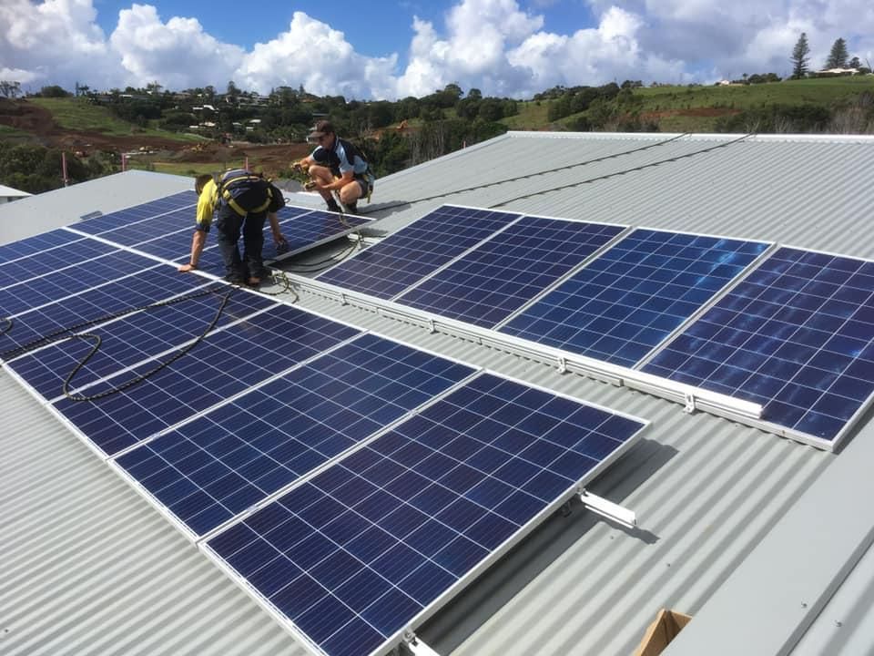 Two Men Are Installing Solar Panels on The Roof of A Building — Col Groves Electrics Pty Ltd in Wardell, NSW