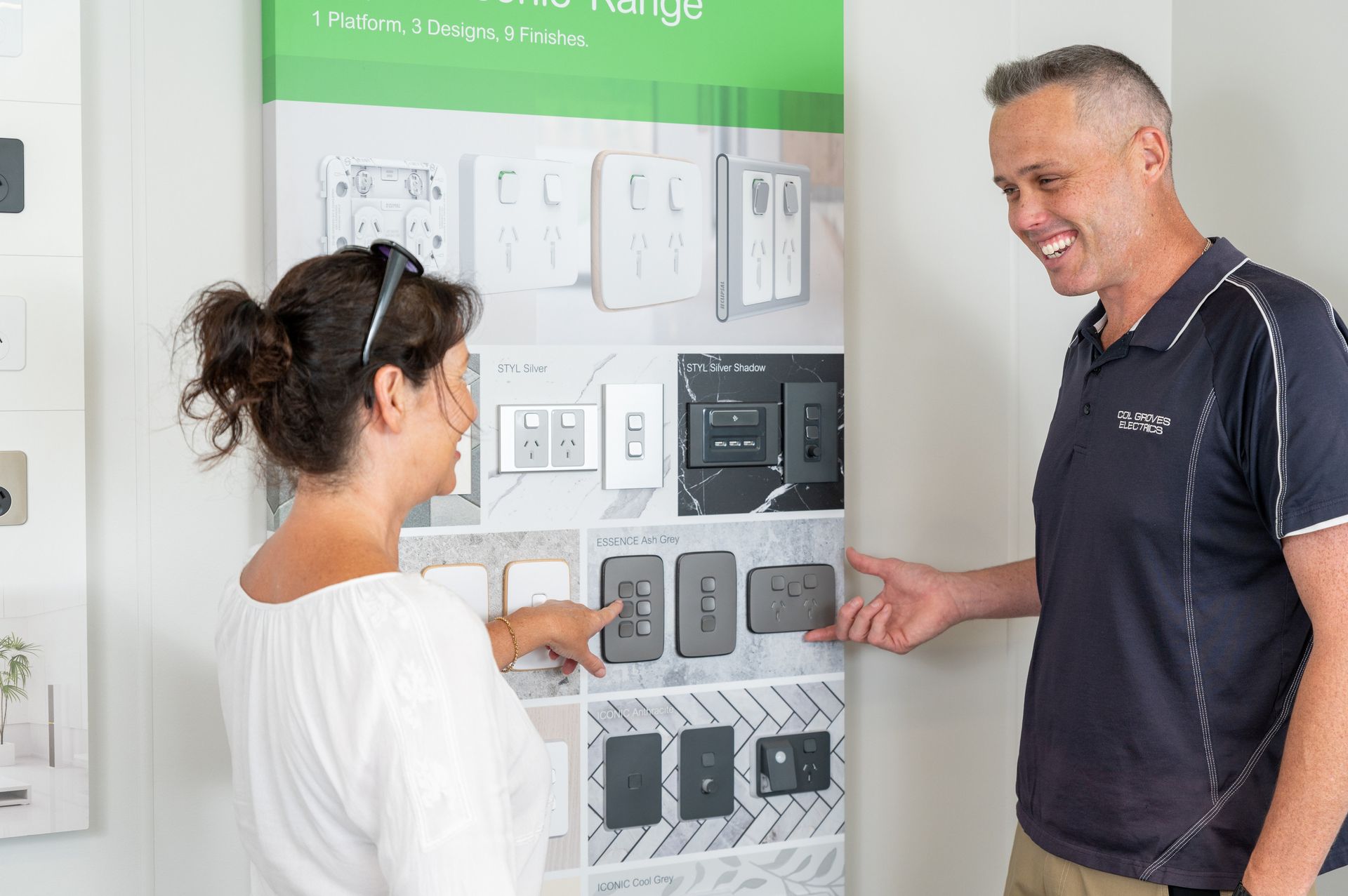 Man and woman looking at a display of light switches, woman points, man smiles — Col Groves Electrics Pty Ltd in Ballina, NSW