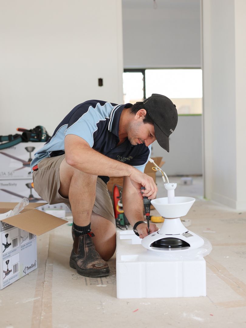 Man installing a ceiling fan in a room under construction — Col Groves Electrics Pty Ltd in Ballina, NSW