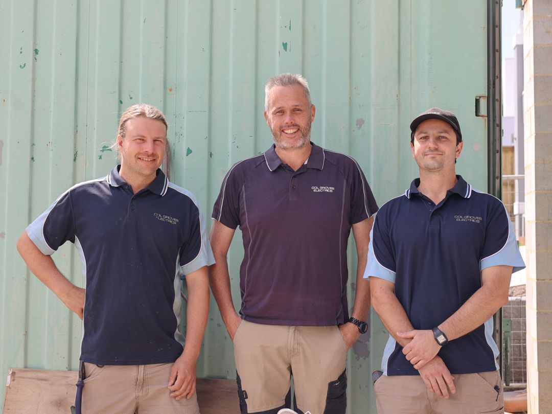 Three men in work shirts standing in front of a green wall — Col Groves Electrics Pty Ltd in Ballina, NSW
