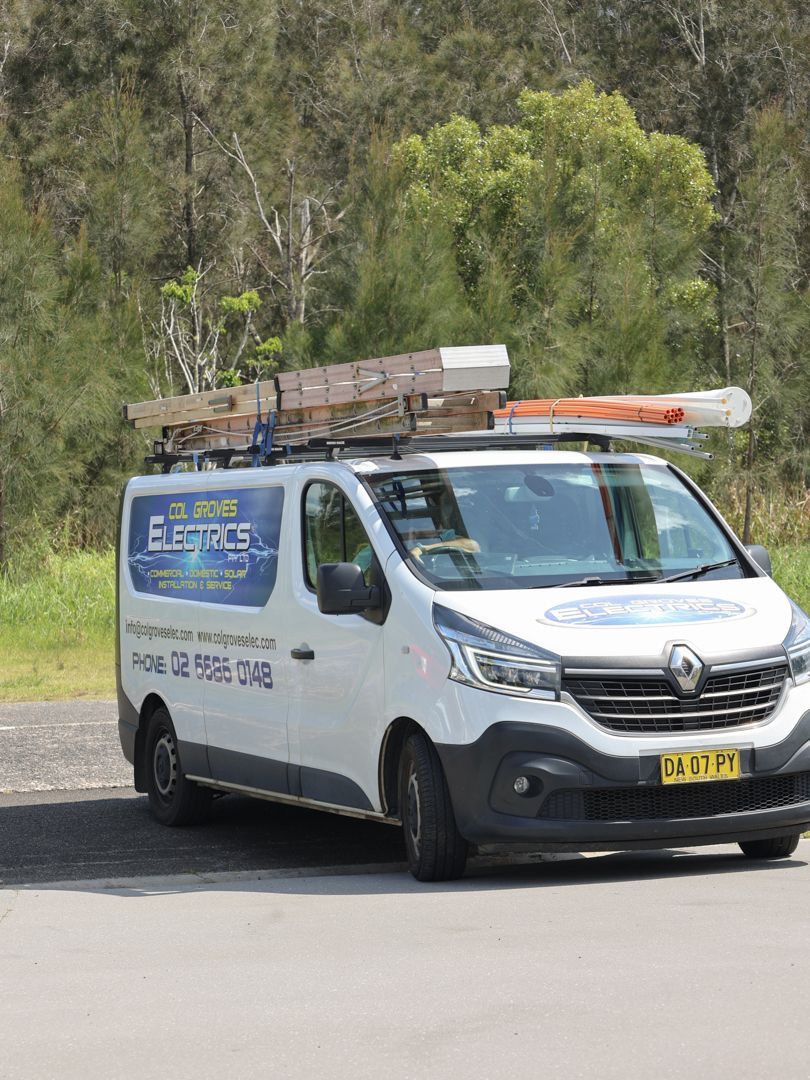 White electrician van with tools on roof parked on road, trees in background — Col Groves Electrics Pty Ltd in Ballina, NSW