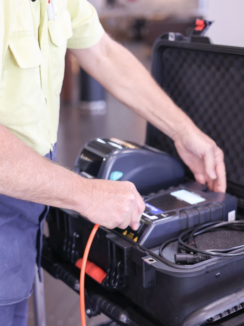Person in yellow shirt connects cables to testing equipment inside a black case — Col Groves Electrics Pty Ltd in Ballina, NSW