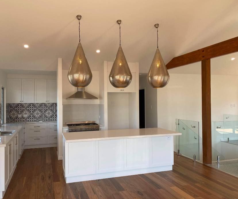 Modern kitchen with white cabinets and wooden floors — Col Groves Electrics Pty Ltd in Ballina, NSW