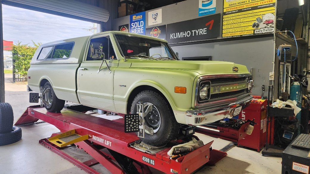 A Green Truck is Sitting on Top of a Red Lift — All Care Car Services Kumho Tyre Platinum Dealer in Kurri Kurri, NSW