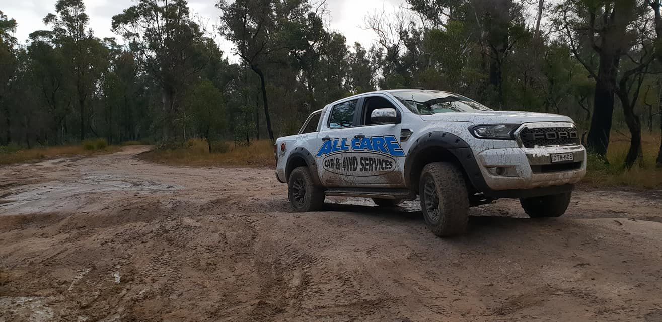 A White Truck is Driving Down a Muddy Road — All Care Car Services Kumho Tyre Platinum Dealer in Kurri Kurri, NSW
