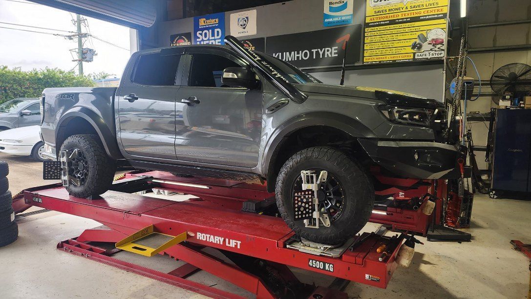 A Truck is Sitting on Top of a Red Lift in a Garage — All Care Car Services Kumho Tyre Platinum Dealer in Kurri Kurri, NSW