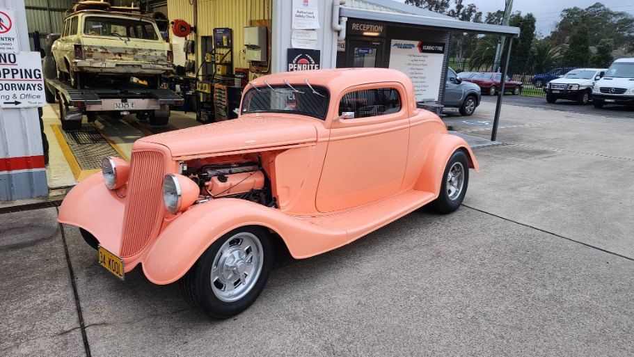 A Pink Car is Parked in Front of a Garage — All Care Car Services Kumho Tyre Platinum Dealer in Kurri Kurri, NSW