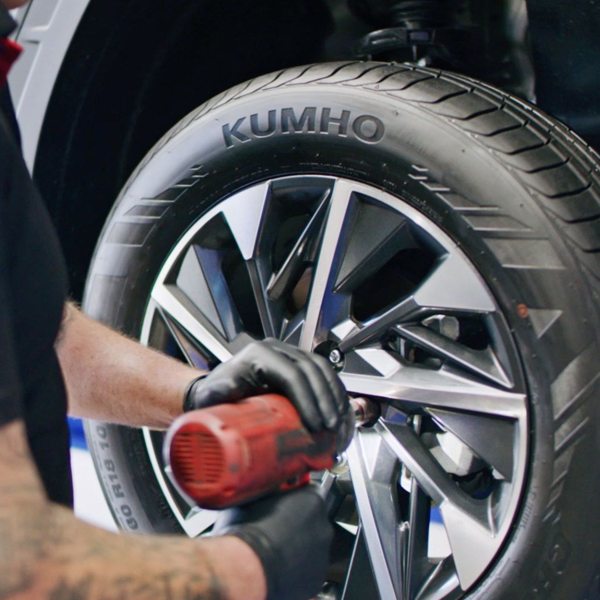 A Man is Working on a Kumho Tire on a Car — All Care Car Services Kumho Tyre Platinum Dealer in Kurri Kurri, NSW